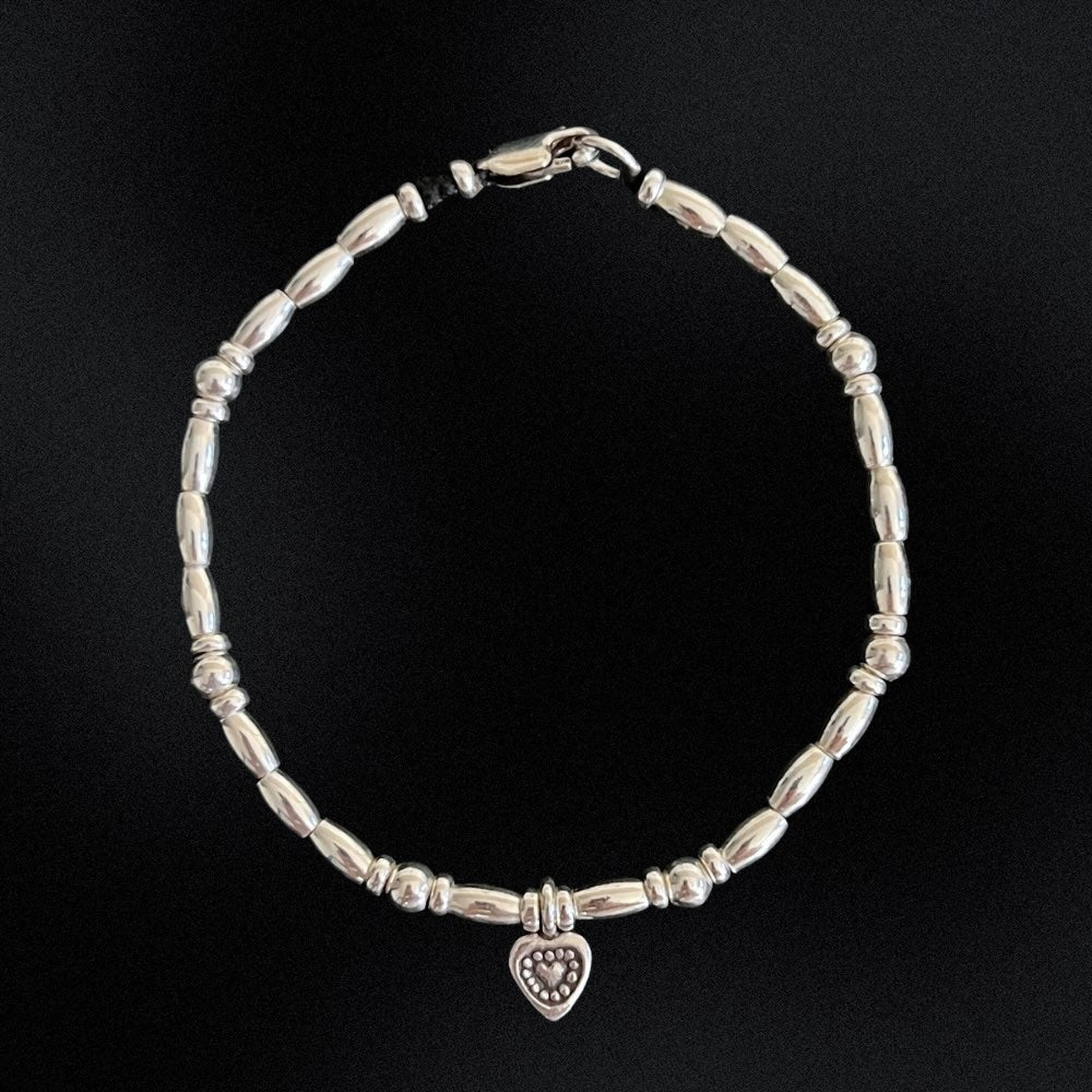 Indulge in the perfect expression of love with our Silver Sweetheart Charm Beaded Bracelet. Made with sterling silver beads, this bracelet is delicately strung on wax string, featuring a charming heart at its centre. Add a touch of elegance to any outfit and let your love shine through!