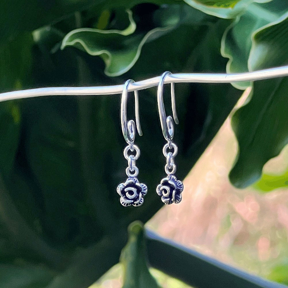 Featuring a gorgeous swirl earring hook that delicately and securely attaches to your ear, these earrings are perfect for any occasion. But what truly makes them unique is the intricately designed Black and Silver rose flower charm that dangles from the bottom of each earring.