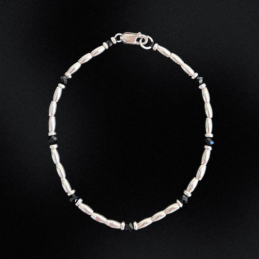 Introducing the Midnight Essence Silver Beaded Bracelet - the perfect accessory to complete any outfit. The centre detail of the bracelet features stunning faceted glass rondelle black beads that catch the light and sparkle brilliantly. Surrounding these gems are delicate silver beads, adding a touch of sophistication and elegance to the design.